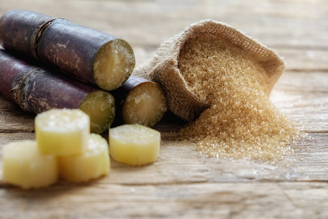 Cana-de-açúcar no formato natural e refinado sobre tábua.