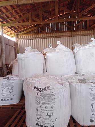 Big Bags de fertilizantes empilhados em duas camadas, sobre paletes dentro do galpão de armazenamento.