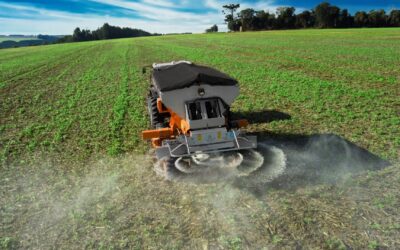 Maquinário agrícola fazendo aplicação de fertilizantes numa lavoura.