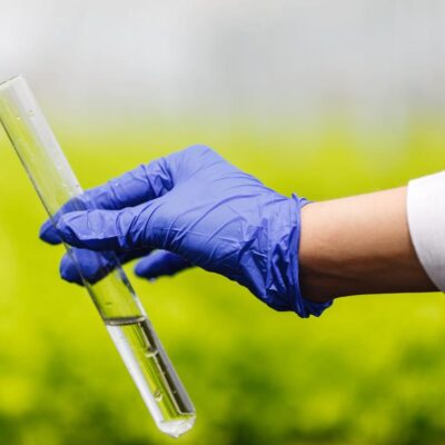pessoas com luva na mão segurando tubo de ensaio com bioinsumos dentro