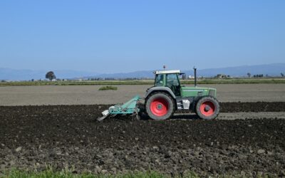 Um trator verde está usando uma arado para preparar o solo para o plantio