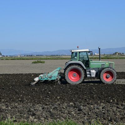 Um trator verde está usando uma arado para preparar o solo para o plantio