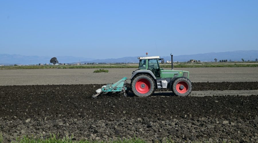 Um trator verde está usando uma arado para preparar o solo para o plantio